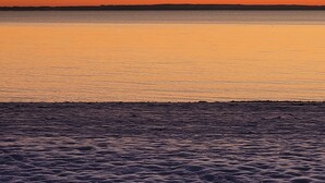 Een strand met een kalme zee en een zonsondergang.