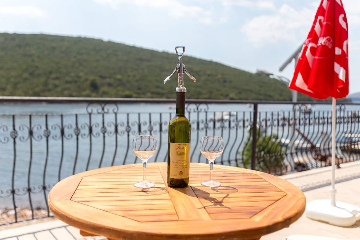 Uma mesa de madeira com uma garrafa de vinho e duas taças, com vista para um lago pitoresco.