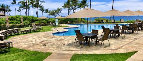 Zona de piscina con sillones, sombrillas y una vista despejada del océano.