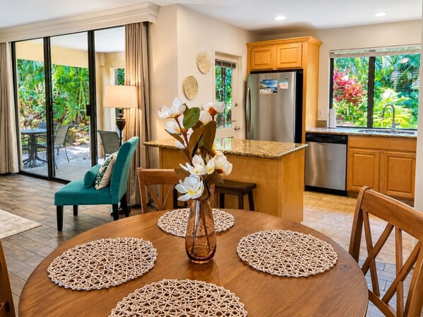 Un coin repas avec une table ronde, des chaises et un vase rempli de fleurs.