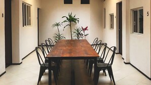 A conference room with a long table, black chairs, and potted plants. - Estacion Alameda (Orizaba)