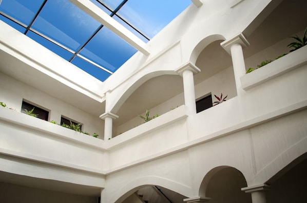 Ein mehrgeschossiges Atrium mit weißen Wänden, mehreren Bögen und Oberlichtern.