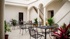 A spacious outdoor patio with multiple tables and chairs, surrounded by white walls and arches. - Estacion Alameda (Orizaba)