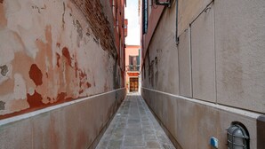 A narrow alleyway with stone flooring and walls showing signs of wear. - Garden Apartment (Venice)