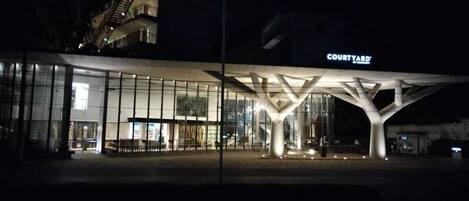 A modern hotel with a glass facade, a prominent 'Courtyard' sign, and a staircase leading to the upper levels.