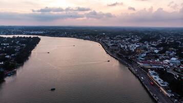 An aerial view of a river with boats, a bridge, and a cityscape with buildings and roads.