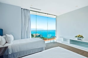A modern hotel room with a large balcony, a bed, a small table, and a vase of flowers.