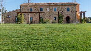 Un edificio de piedra con techo de tejas, ventanas de arco y un campo verde al frente.