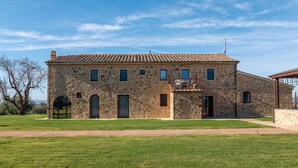 Un edificio de piedra con techo de tejas, ventanas arqueadas y un pequeño balcón.