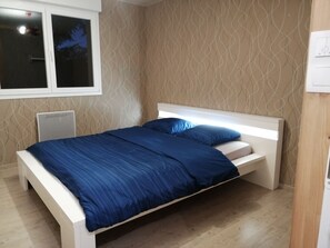 Un dormitorio con cama, ventana y pared con diseño.