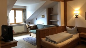 Una habitación acogedora con techo inclinado, una cama, un escritorio y una ventana.