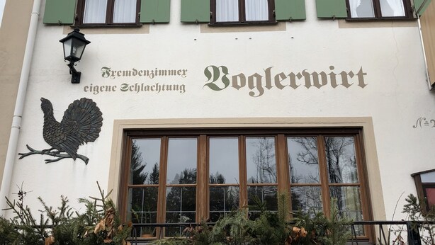 Un edificio con un cartel que dice "Fremdenzimmer eigene Schlaftung" y "Boglermwirt".