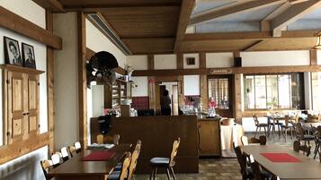 A restaurant with wooden beams, a central counter, and multiple dining tables and chairs.