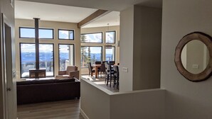 Uma sala de estar moderna com uma janela grande, um espaço de jantar e vista para montanhas.