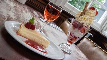 A dessert plate with a slice of cheesecake and a glass of rose wine.