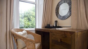 Uma mesa de madeira com um espelho, uma cadeira de vime e uma janela com cortinas.