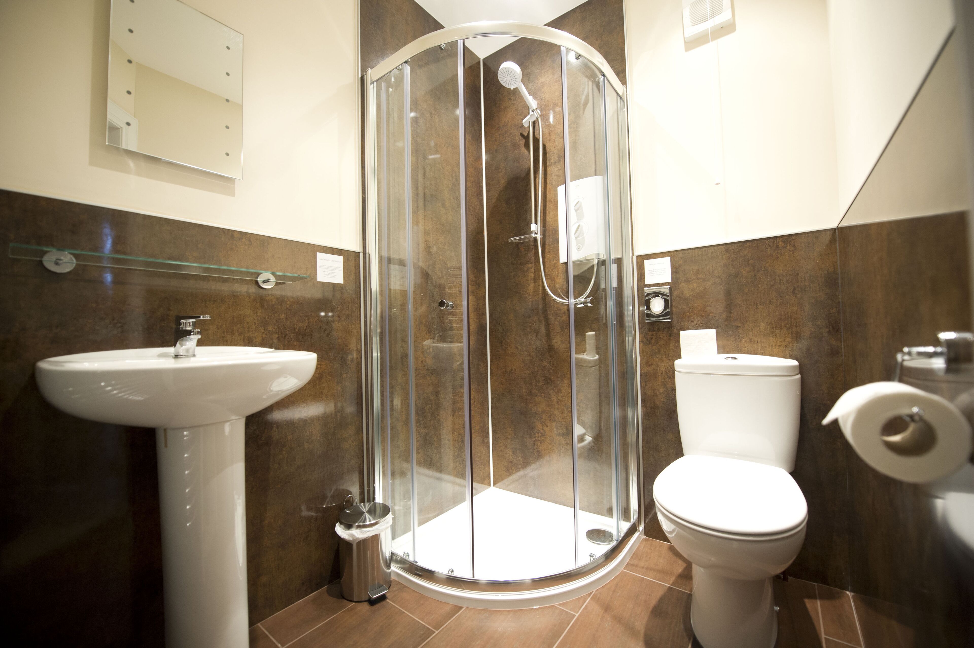 A bathroom with a glass-enclosed shower, a white sink, and a toilet.