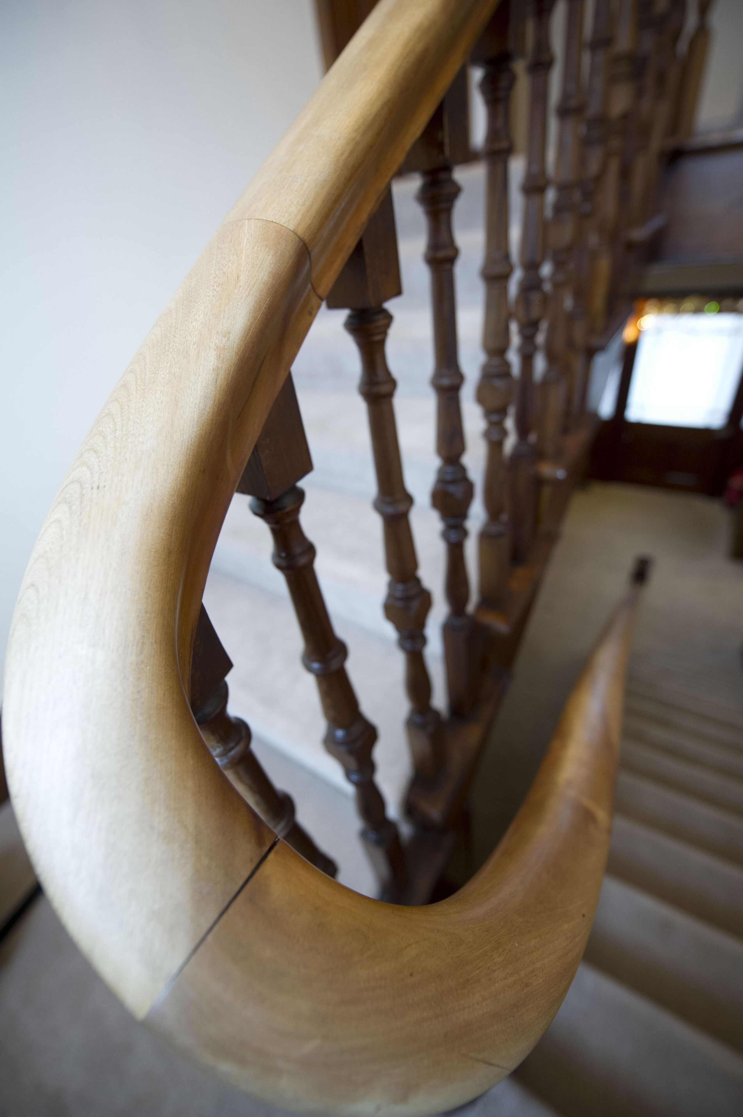 Un escalier en bois avec une main courante incurvée et une balustrade en bois.
