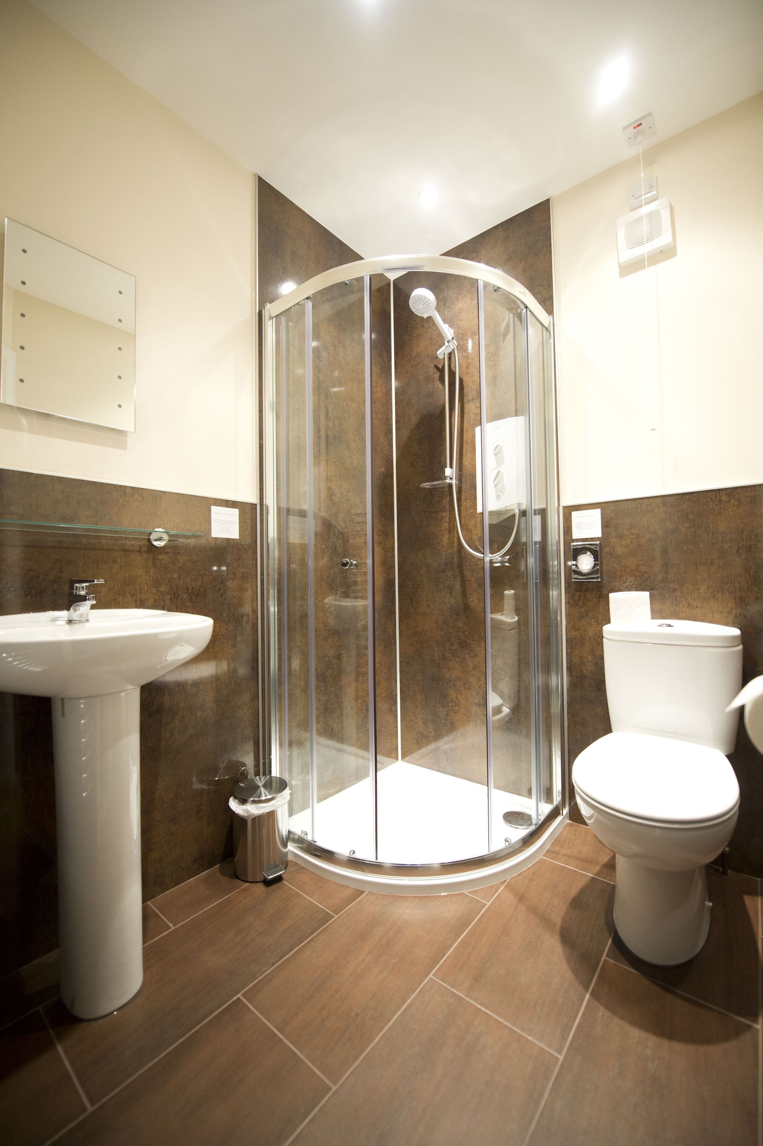 A modern bathroom with a glass-enclosed shower, a sink, and a toilet.