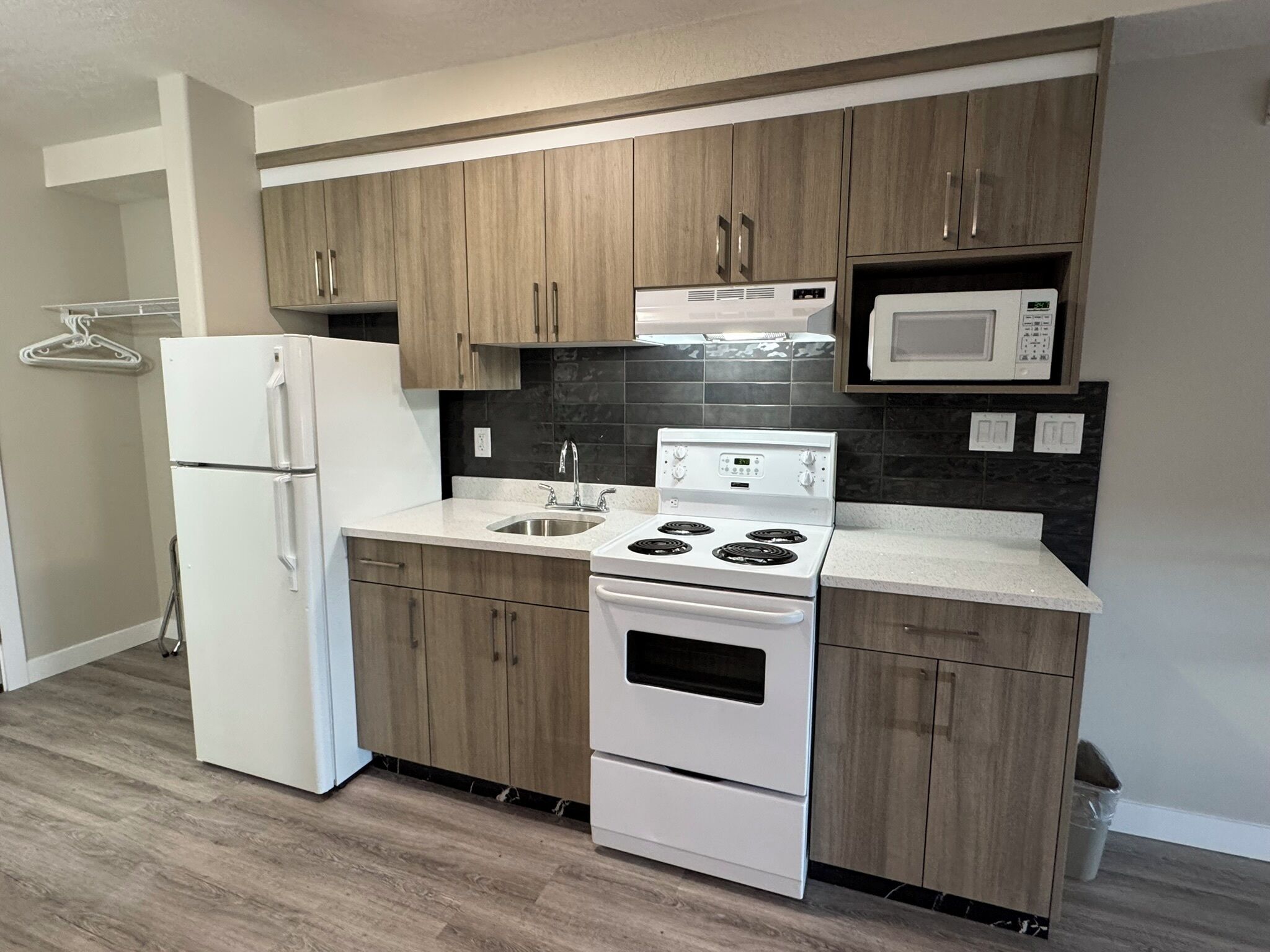 A modern kitchen with wooden cabinets, a white refrigerator, a stove, and a microwave.