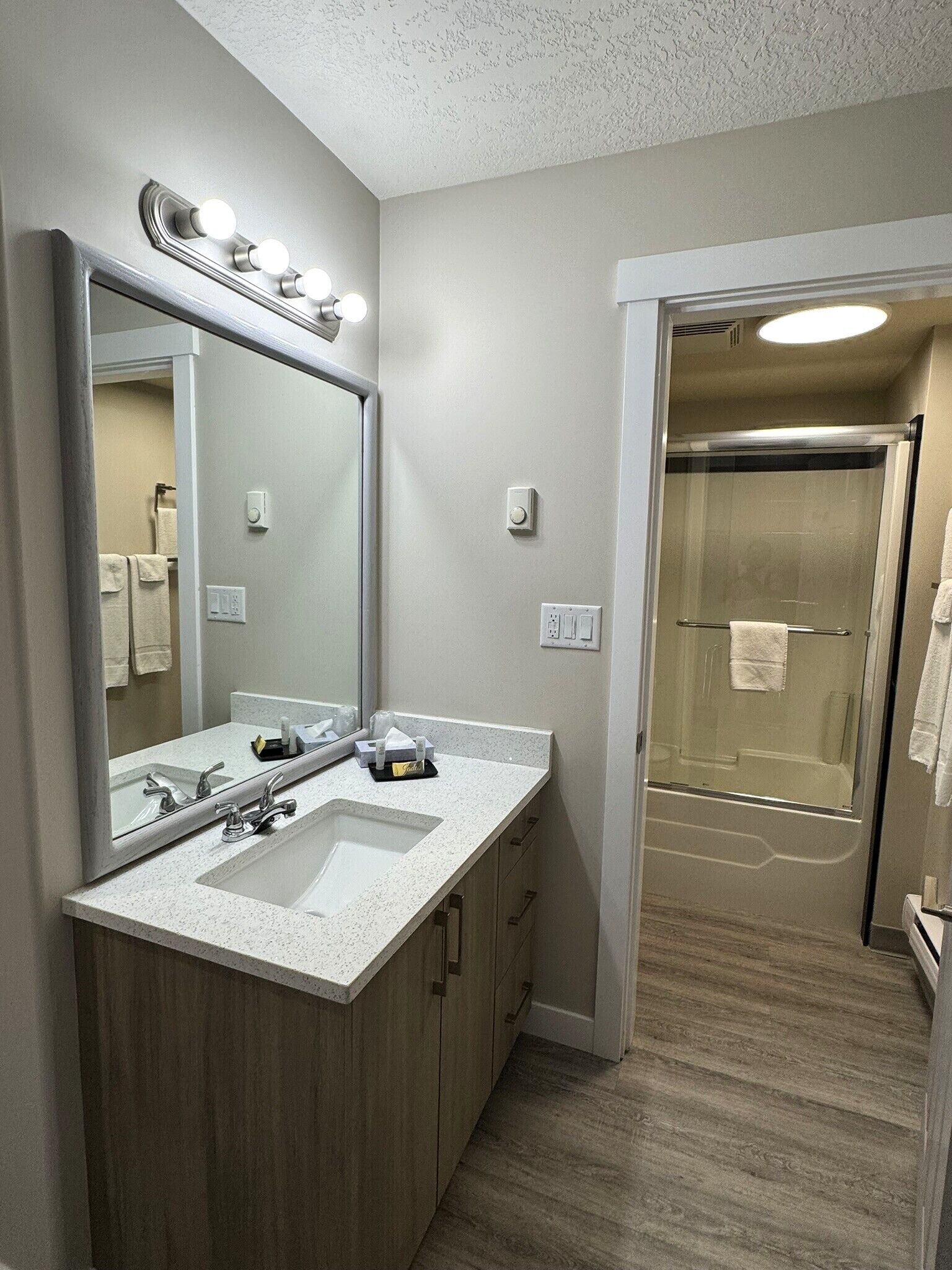 A modern bathroom with a large mirror, two sinks, and a glass shower enclosure.