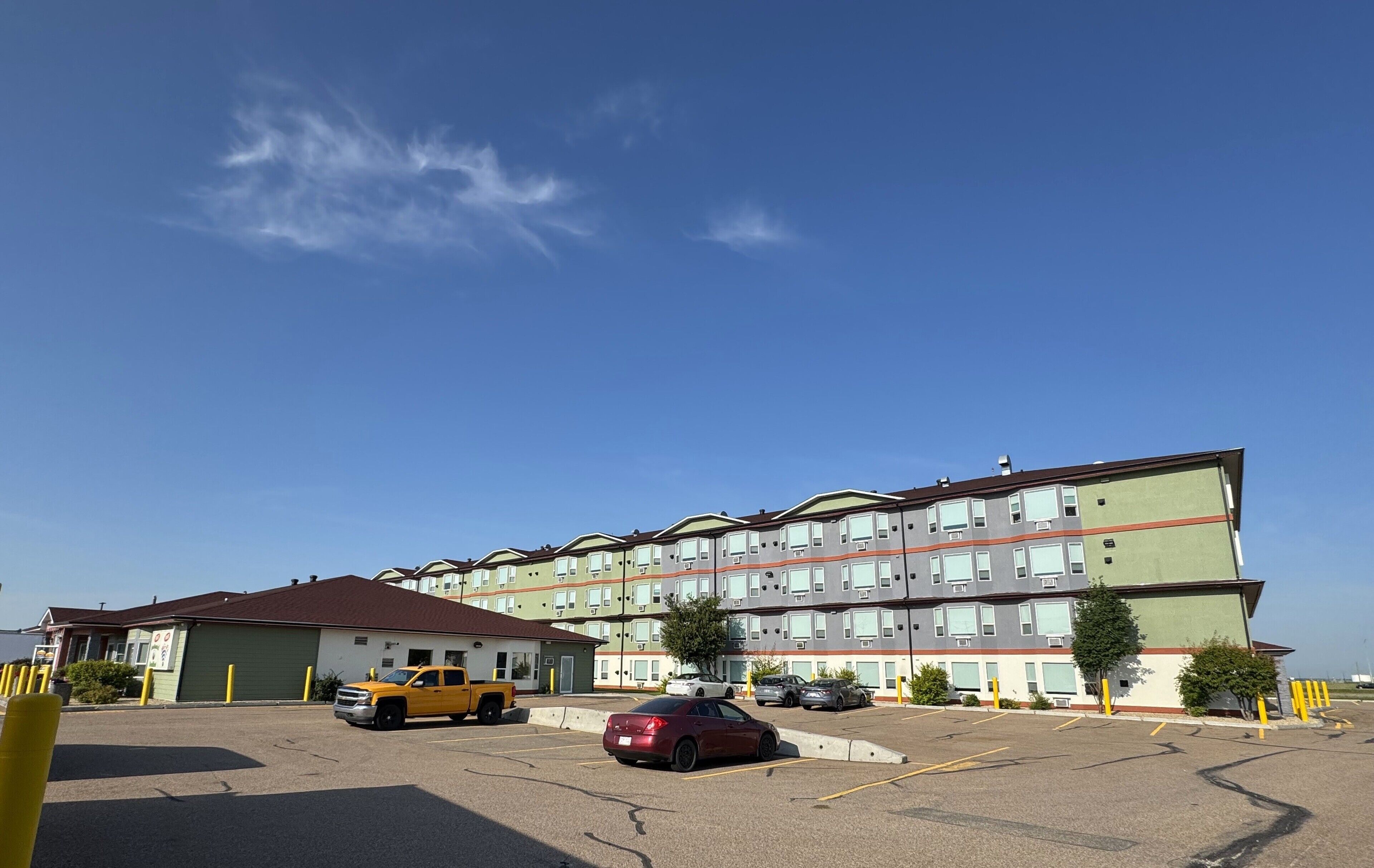 A multi-story residential building with a parking lot in front.