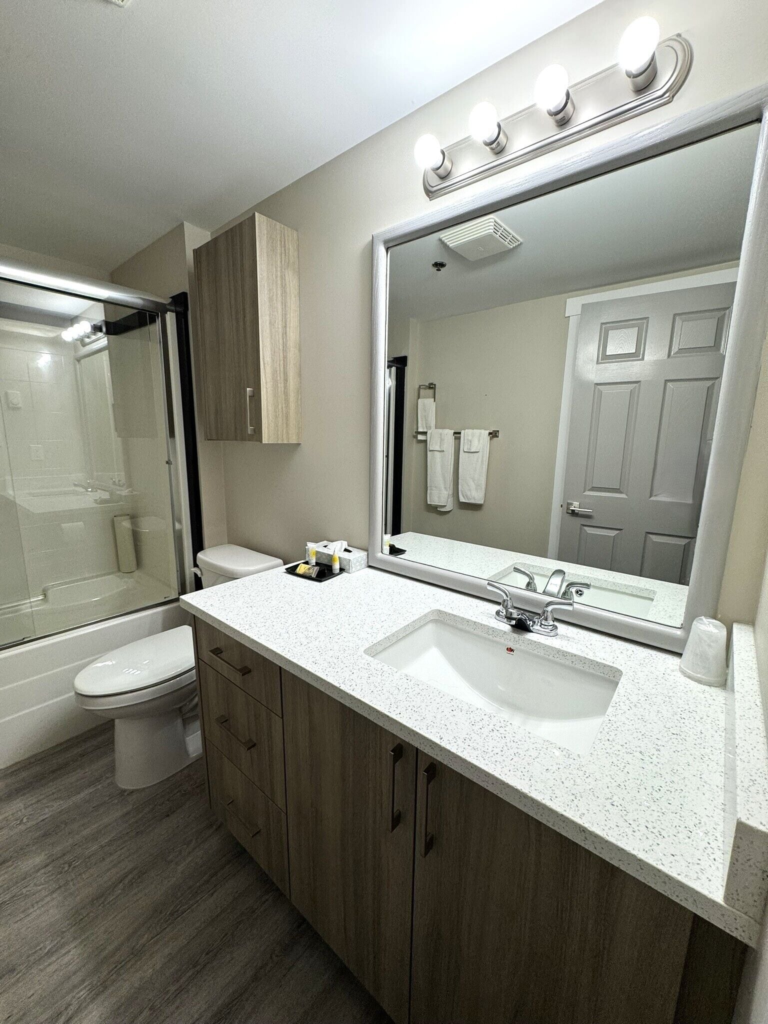 Une salle de bain moderne avec un lavabo blanc, un grand miroir et une cabine de douche en verre.