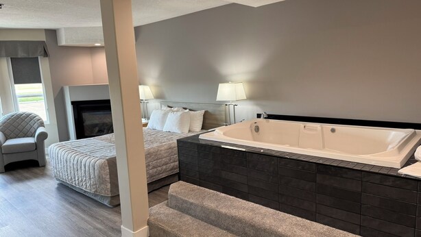 Habitació d'hotel moderna amb una banyera gran, una llar de foc i una zona d'estar confortable.