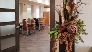 Zona de recepció amb un disseny modern, que inclou un taulell de recepció de fusta, una zona d'estar amb seients i una decoració floral.