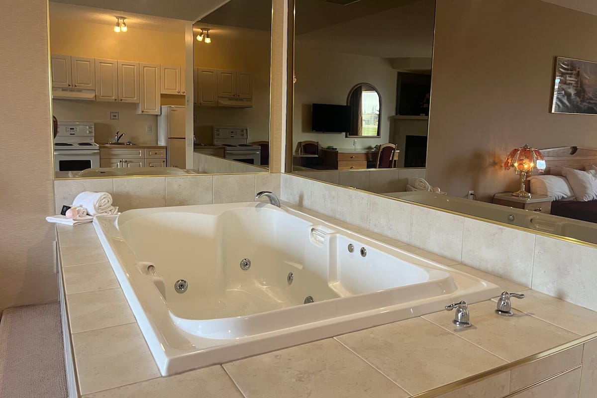 A modern bathroom with a large bathtub, a double sink, and a large mirror.