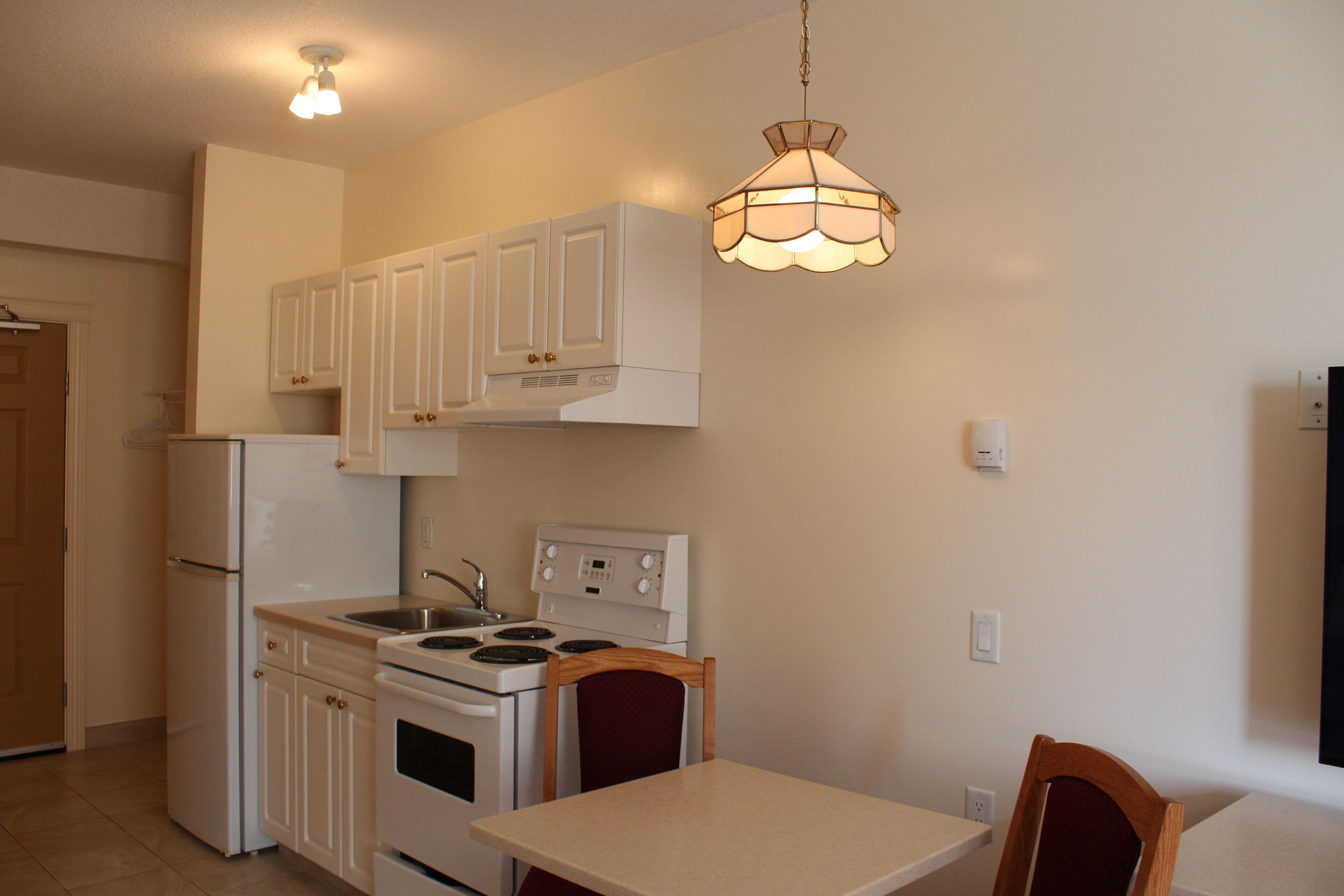 A kitchen with white cabinets, a stove, and a table with chairs.