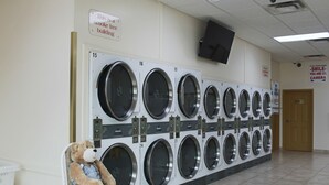 A laundry room with multiple washing machines, a teddy bear, and a sign indicating it is a smoke-free building. - Western Budget Motel - Ponoka (Ponoka)