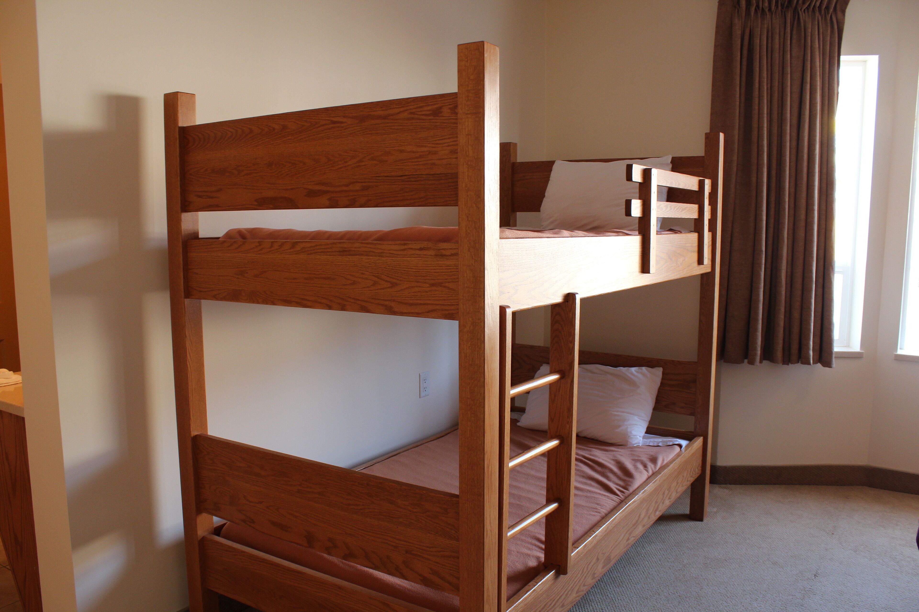 A bunk bed with a wooden frame and a single mattress on the lower bunk.