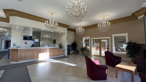 A reception area with a wooden counter, a TV, and a chandelier. - Western Budget Motel - Ponoka (Ponoka)