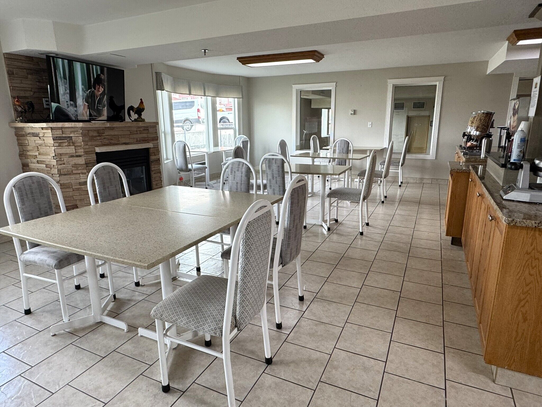 A spacious dining area with a long table and multiple chairs, a kitchen area with a wooden counter, and a stone fireplace.