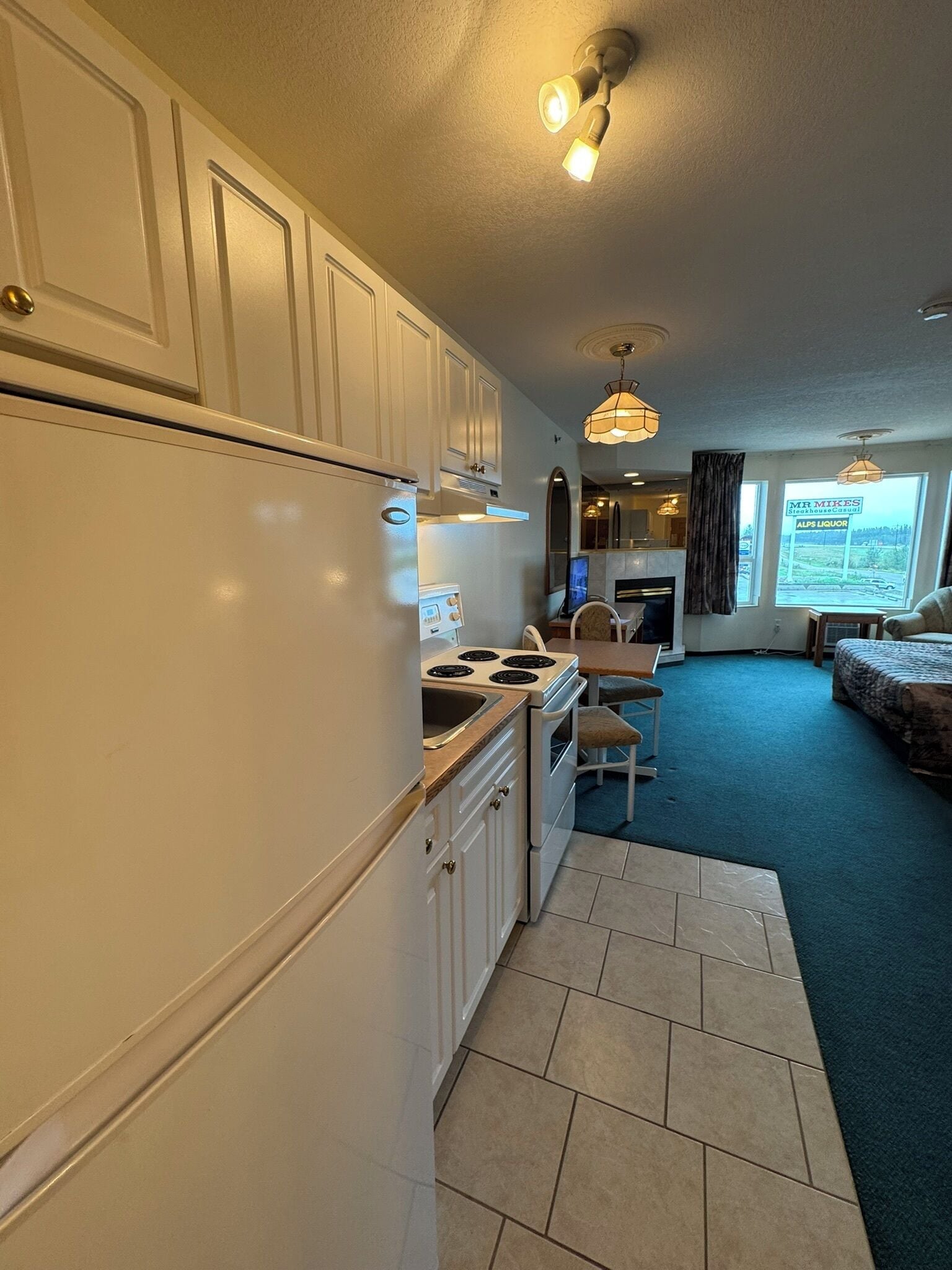 A compact kitchen with white cabinets, a stove, and a dining area with a table and chairs.