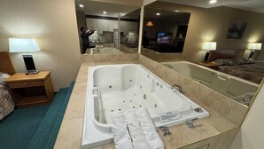 A modern bathroom with a large bathtub, a mirror, a sink, and a vanity. - Western Budget Whitecourt 1 & 2 (Whitecourt)