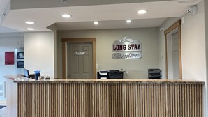 A reception desk with a 'Long Stay Western' sign, a 'Manager Office Staff Only' door, and a computer. - Western Budget Whitecourt 1 & 2 (Whitecourt)