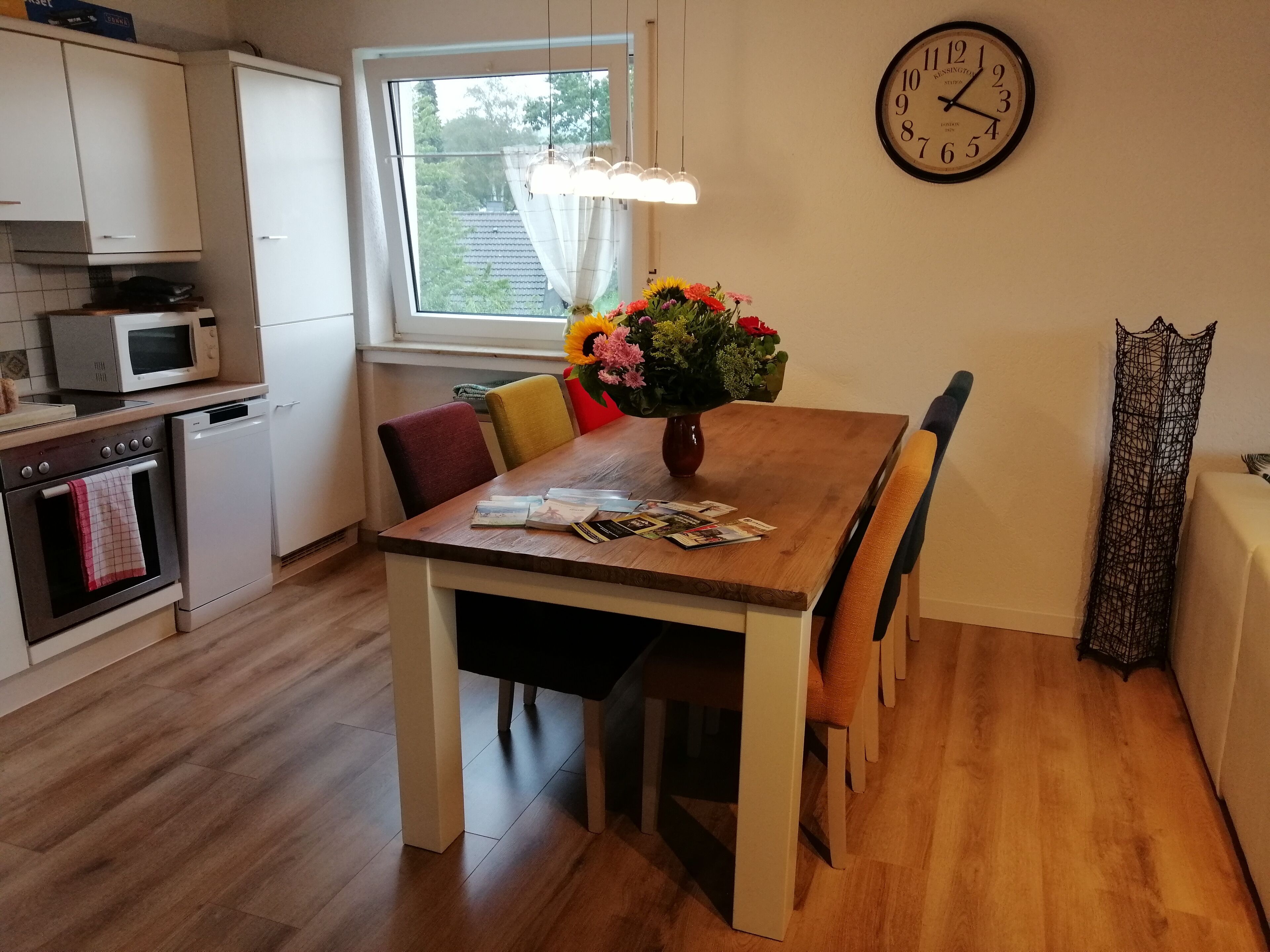 A kitchen with white cabinets, a microwave, an oven, and a dining table with chairs.