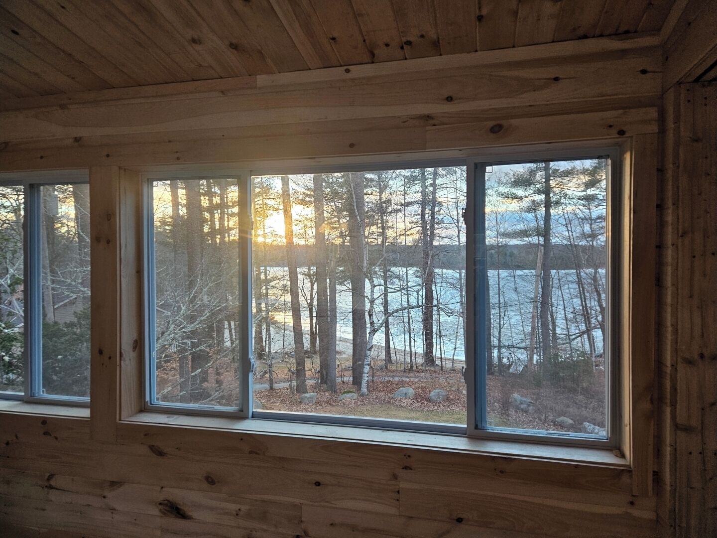Een chaletinterieur met een groot raam dat uitzicht biedt op een bebost gebied.