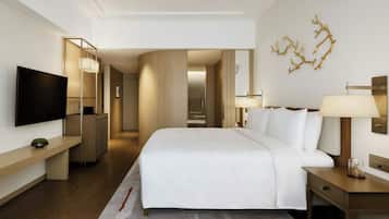 Ein modernes Hotelzimmer mit einem großen Bett, Nachttischen, einem Flachbildfernseher und einem Spiegel.