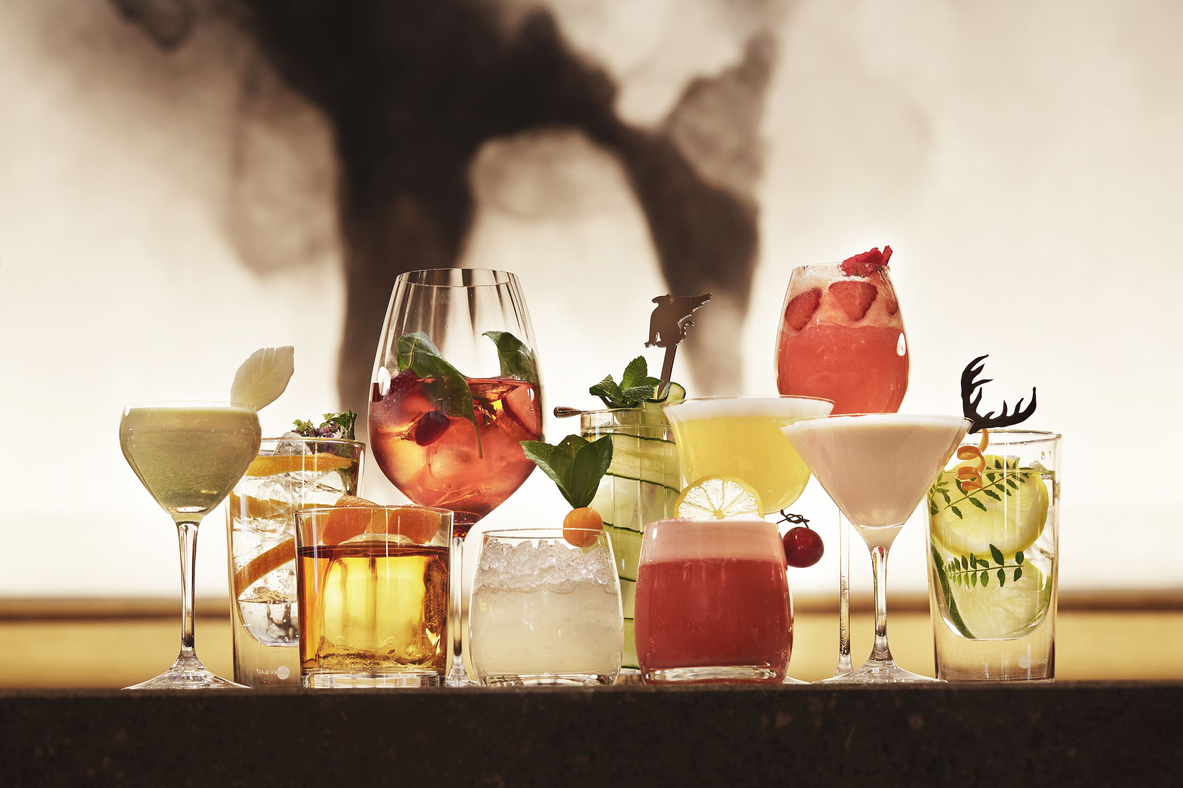 Une variété de boissons servies dans différents types de verres, notamment un martini, un highball et un cocktail agrémenté d’un fruit.