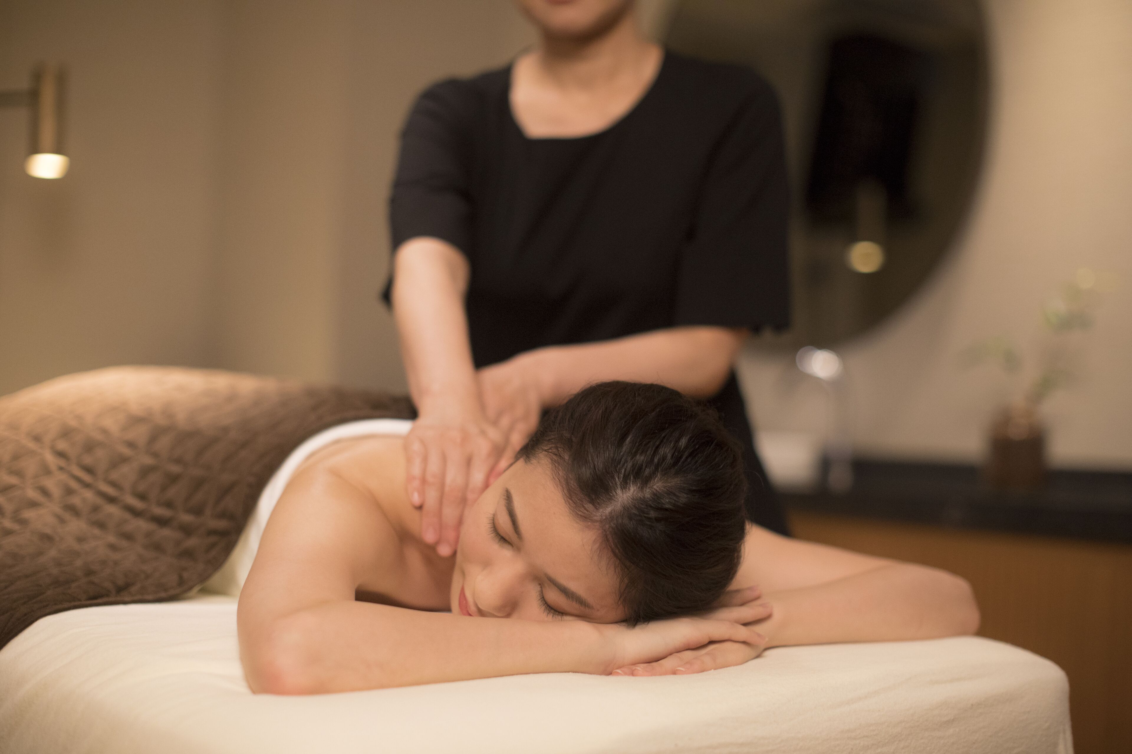 En person modtager massage i et rum med massagestol og massør.