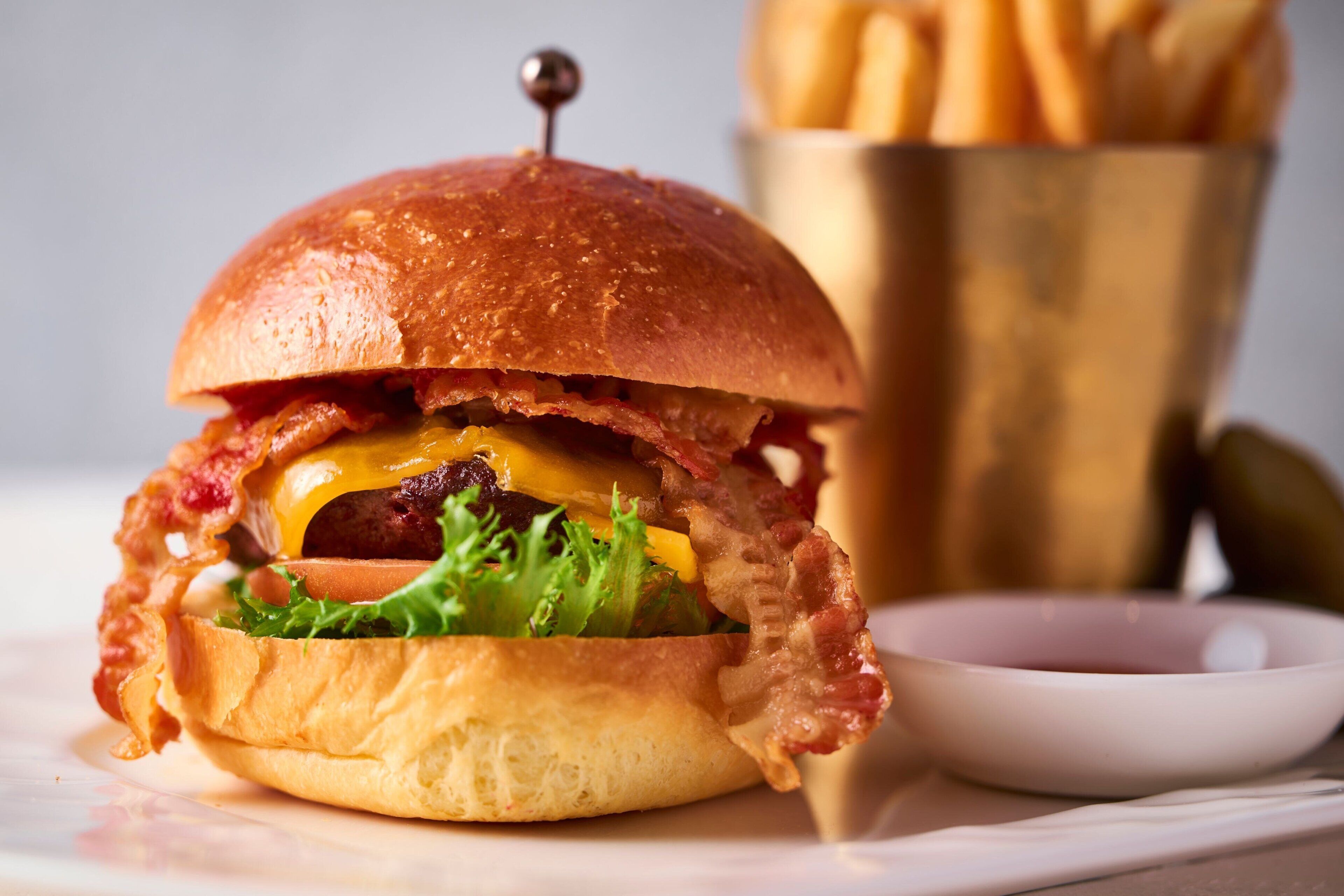 A burger with a crispy bun, topped with lettuce, cheese, and a patty, accompanied by a side of fries.