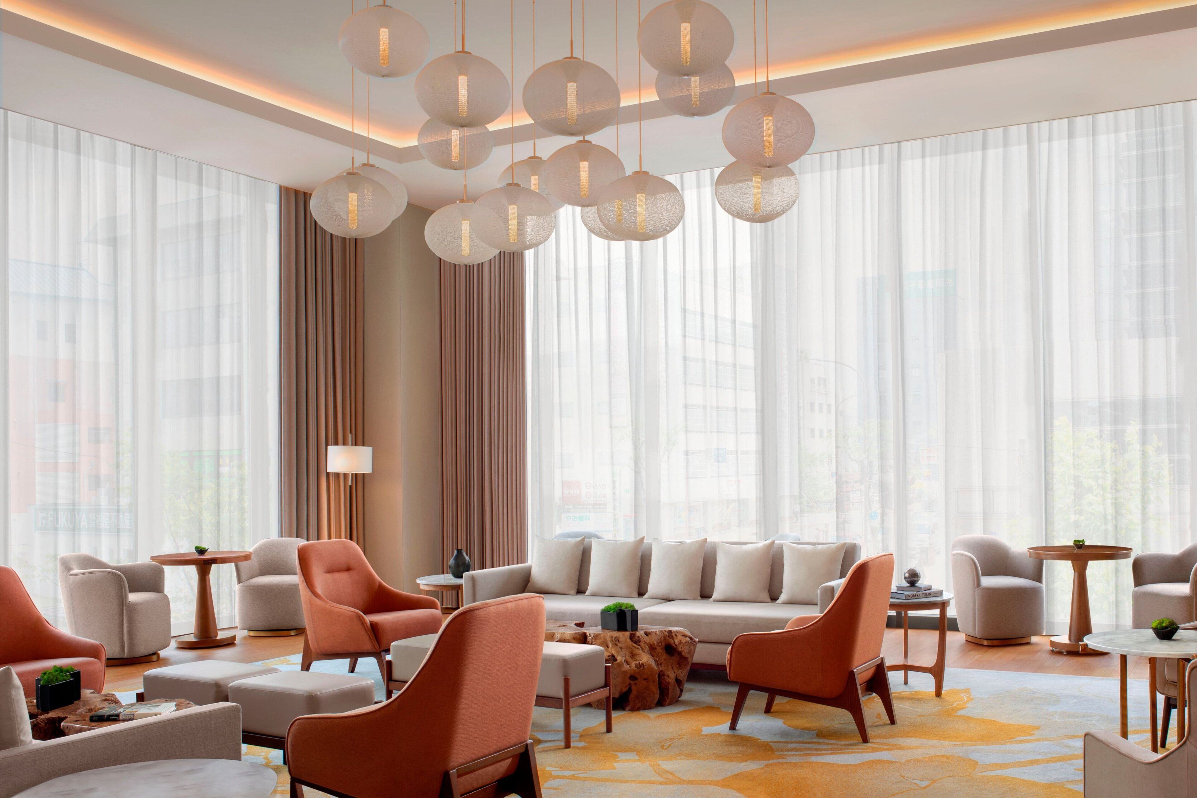 Un moderno hall de hotel con un conjunto de sofás, sillones, una mesita de centro y una mesita auxiliar de madera.