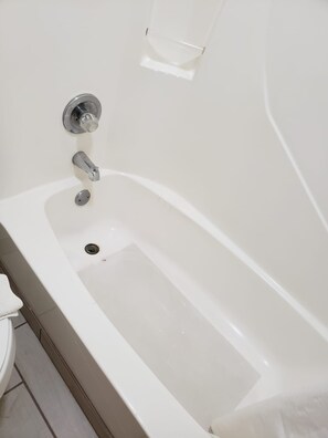 A white bathtub with a chrome faucet and a drain. - Value Inn & Suites (Salina)