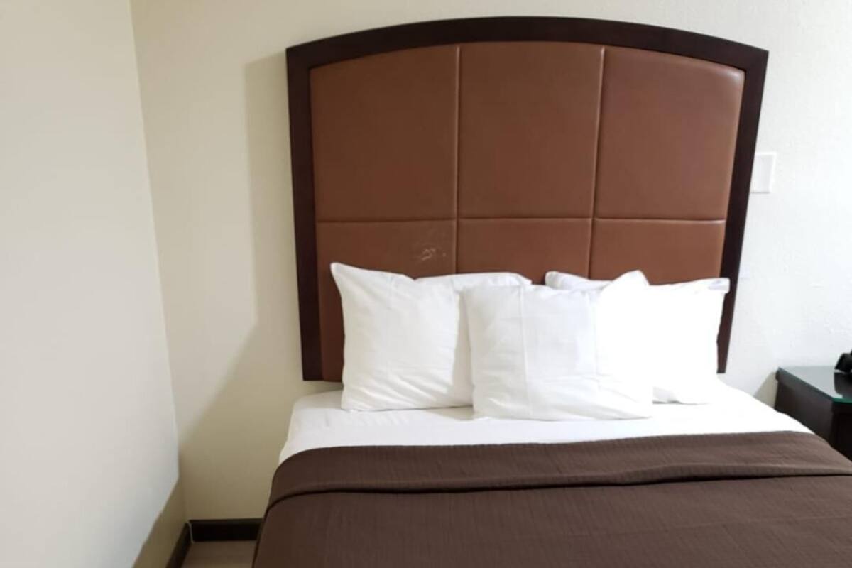 A hotel room with a bed, a headboard, and a nightstand.
