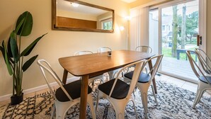Ein Essbereich mit einem Holztisch, sechs Stühlen, einem großen Spiegel an der Wand und einem Blumentopf.