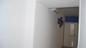 A hallway with a white wall, a ceiling-mounted air conditioner, and a door leading to another room. - in the real heart of Sorrento (Sorrento)