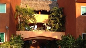 A hotel with a central courtyard, palm trees, and a thatched roof structure.